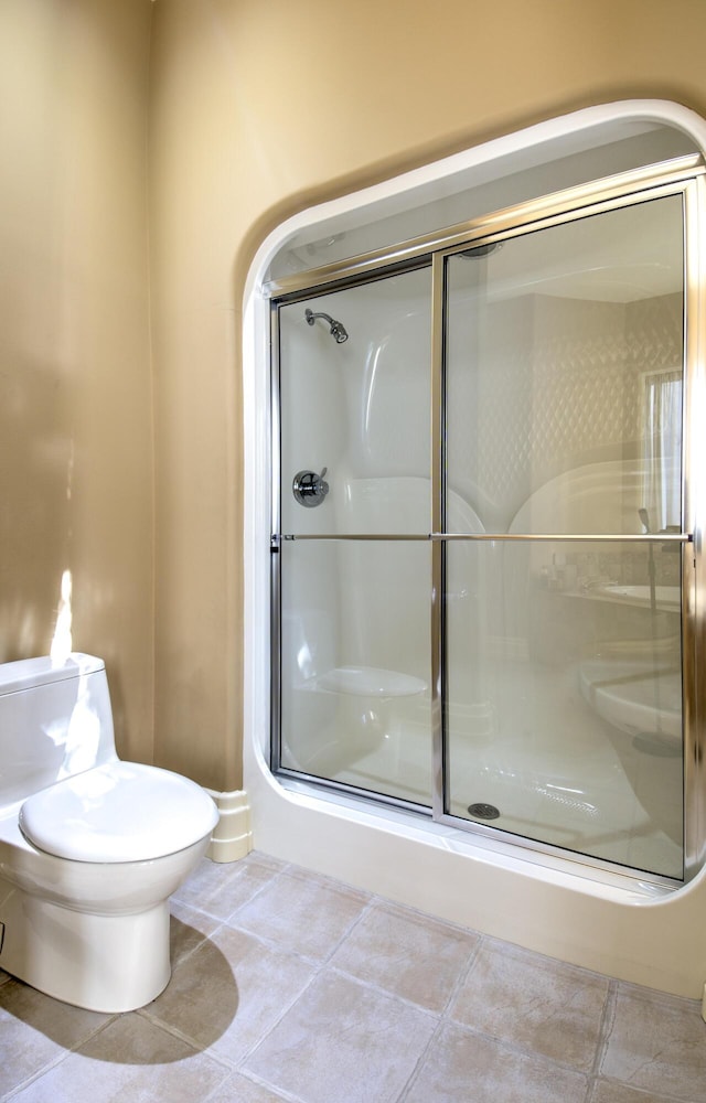 bathroom featuring a stall shower, toilet, and tile patterned floors