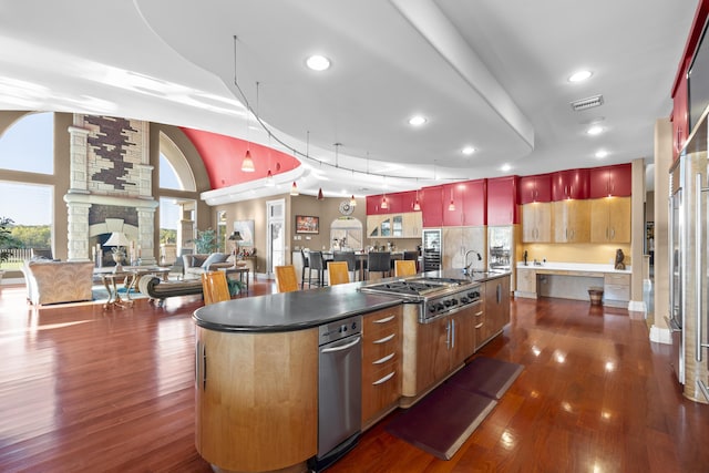 kitchen featuring stainless steel gas cooktop, a large island with sink, dark wood finished floors, dark countertops, and recessed lighting