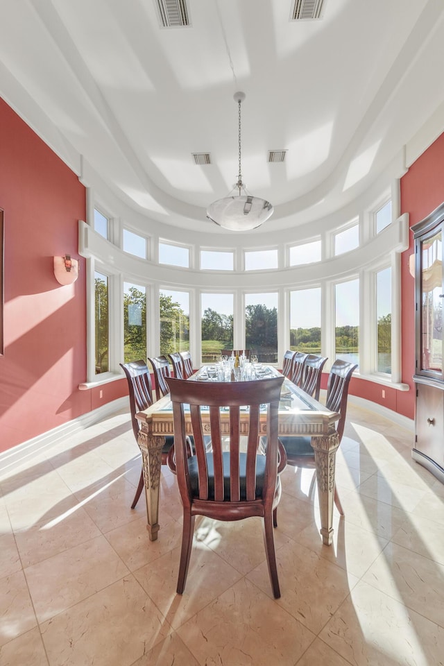 dining area with a tray ceiling, baseboards, and light tile patterned flooring
