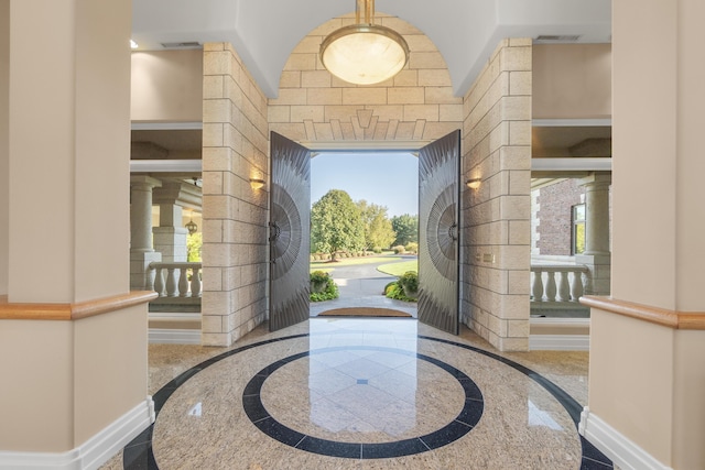 entrance foyer featuring inlaid floor details, ornate columns, baseboards, and healthy amount of natural light