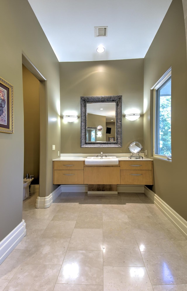 bathroom with baseboards, a bidet, vanity, and tile patterned flooring