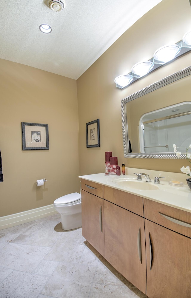full bath with baseboards, vanity, and toilet
