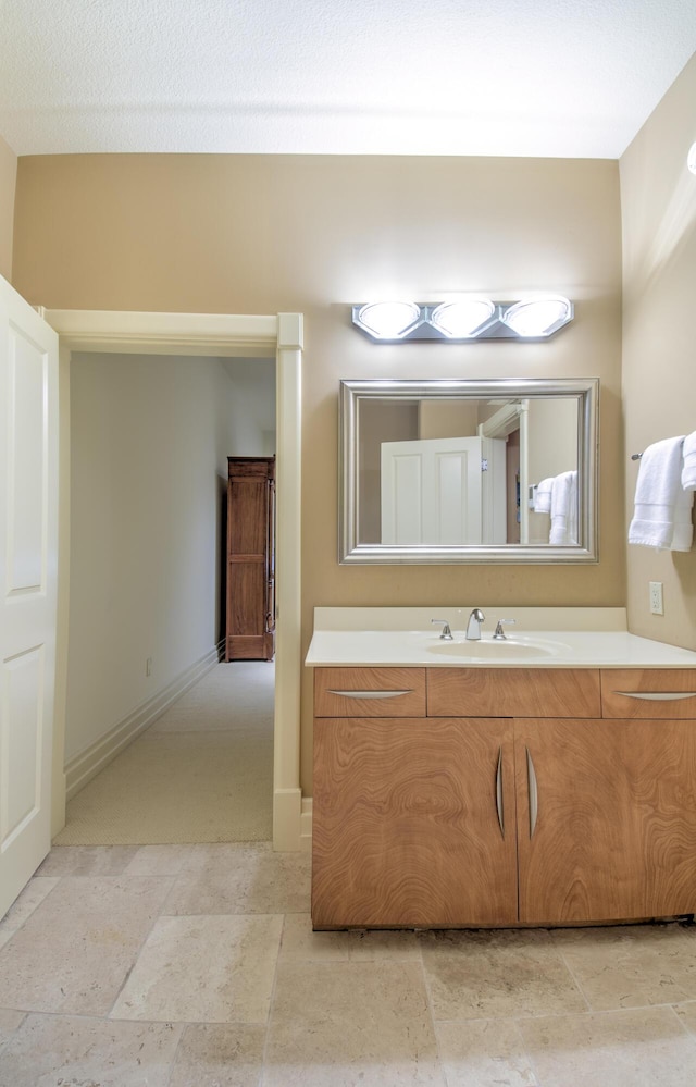 bathroom with stone finish flooring, vanity, and baseboards