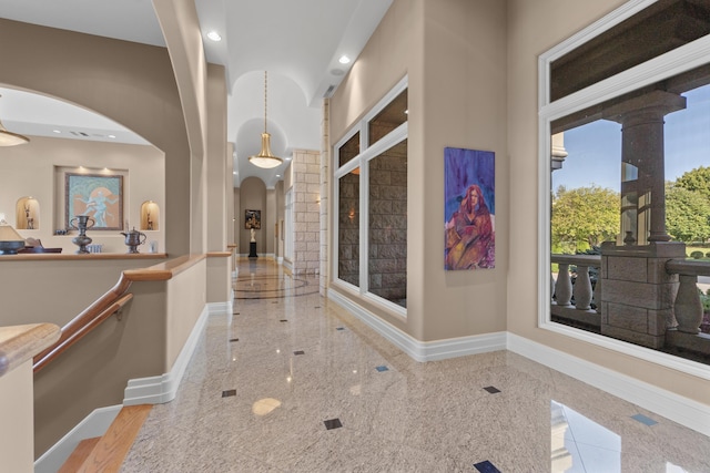 hallway featuring arched walkways, granite floors, baseboards, recessed lighting, and decorative columns