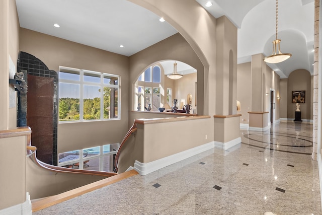foyer entrance with arched walkways, granite floors, baseboards, recessed lighting, and a towering ceiling