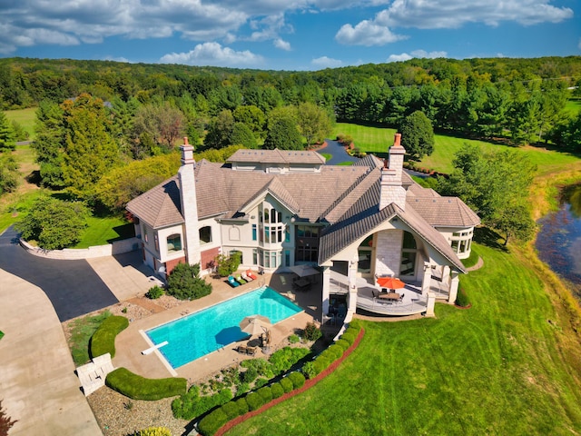 outdoor pool with a view of trees, an outdoor living space, a diving board, and a patio