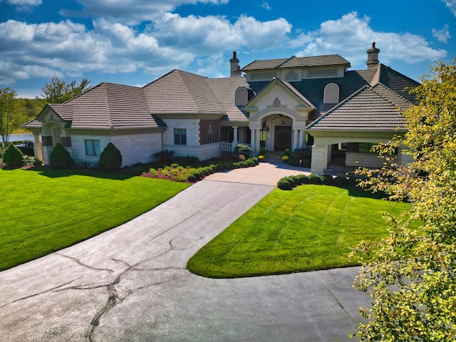 french country style house featuring stone siding, driveway, and a tile roof