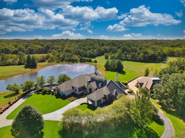 aerial view of property and surrounding area featuring a heavily wooded area and a nearby body of water