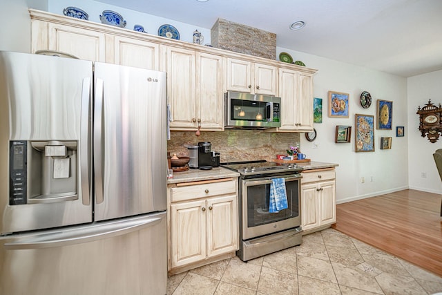 kitchen featuring stainless steel appliances, decorative backsplash, baseboards, and light tile patterned floors