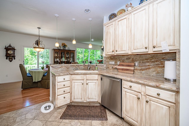kitchen with stainless steel dishwasher, a sink, a peninsula, decorative backsplash, and light stone counters
