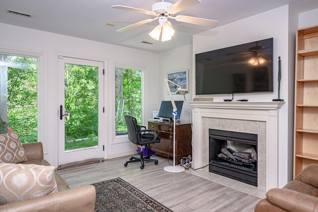 office area featuring a ceiling fan, wood finished floors, and a tiled fireplace