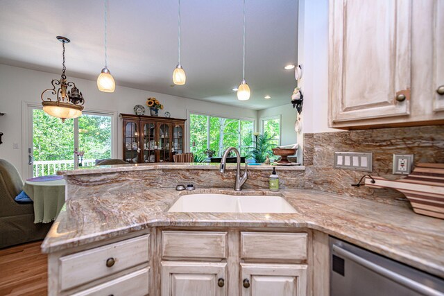 kitchen featuring stainless steel dishwasher, a sink, light brown cabinets, and backsplash