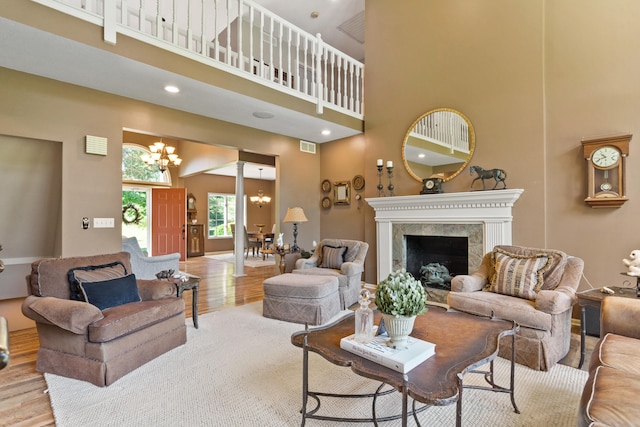 4700 E Deer Noll Rd, Columbia, MO 65201 - living room featuring a chandelier, a towering ceiling, wood finished floors, and a premium fireplace