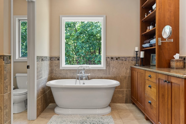 4700 E Deer Noll Rd, Columbia, MO 65201 - bathroom with tile walls, toilet, plenty of natural light, a freestanding tub, and a wainscoted wall