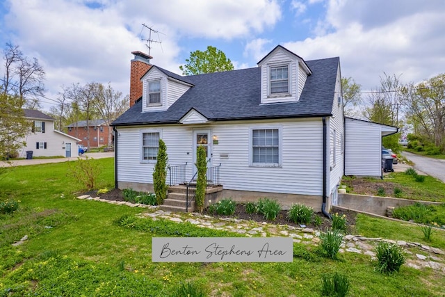 new england style home featuring a front yard, a chimney, and roof with shingles