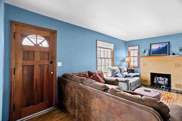 living room with wood finished floors, healthy amount of natural light, and a brick fireplace