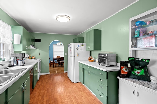 kitchen featuring green cabinets, a sink, white appliances, and arched walkways