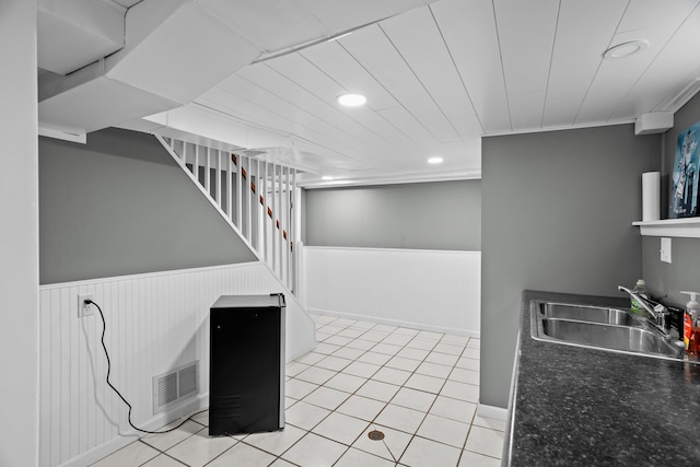 kitchen featuring a sink, recessed lighting, a wainscoted wall, light tile patterned floors, and dark countertops