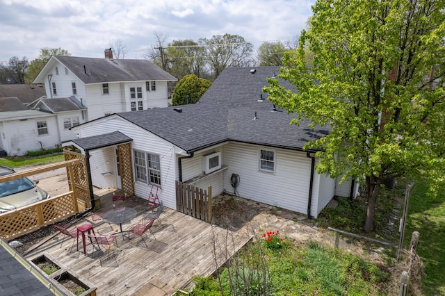 rear view of property with a deck and roof with shingles