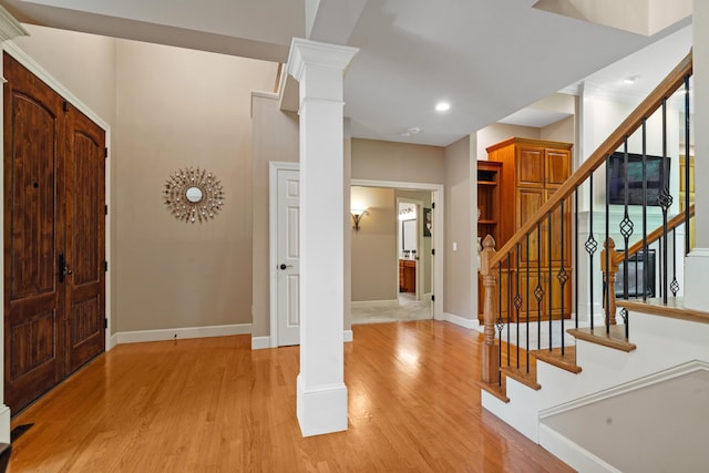 entrance foyer with decorative columns, light wood-type flooring, baseboards, stairs, and recessed lighting