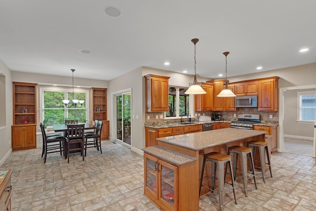 kitchen featuring appliances with stainless steel finishes, baseboards, a sink, brown cabinets, and recessed lighting
