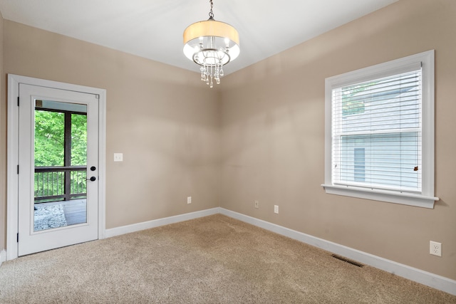 unfurnished room with a chandelier, carpet flooring, healthy amount of natural light, and baseboards