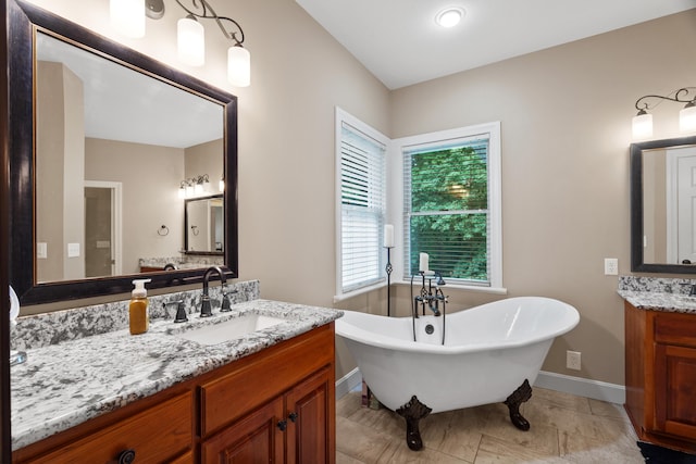 full bathroom featuring a freestanding tub, two vanities, and baseboards