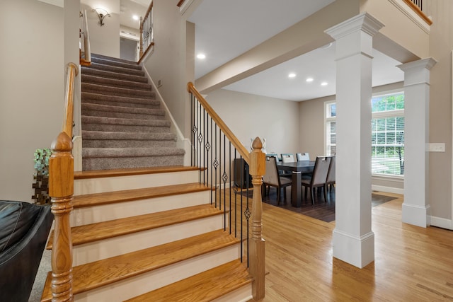 stairs with decorative columns, wood finished floors, recessed lighting, and baseboards
