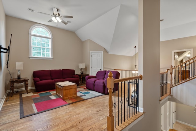 living area with ceiling fan, wood finished floors, vaulted ceiling, and baseboards
