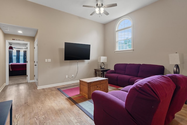 living area featuring light wood-style flooring, baseboards, and a ceiling fan