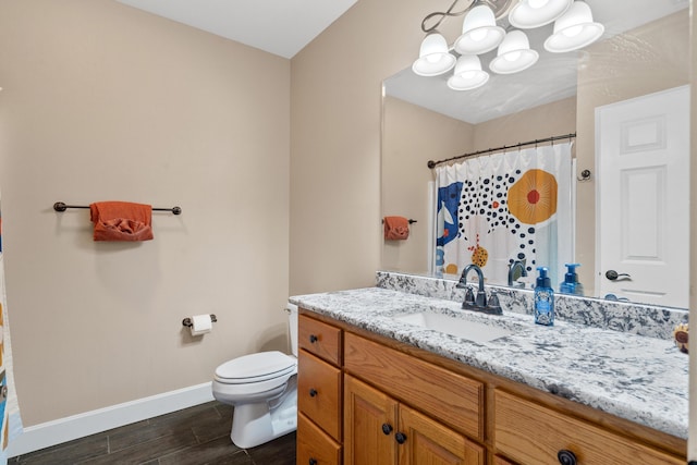 full bathroom with a chandelier, baseboards, wood finished floors, toilet, and vanity