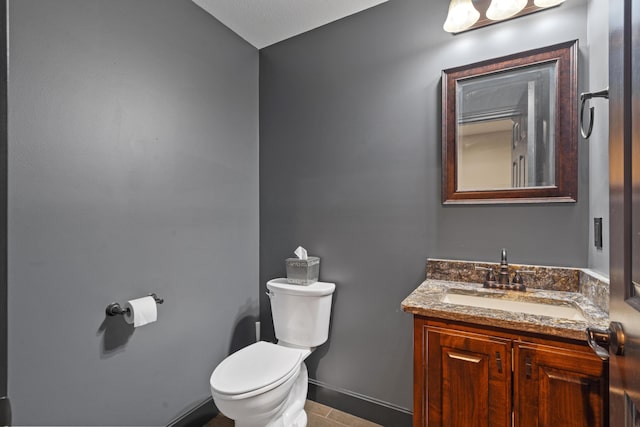 half bath featuring toilet, vanity, and baseboards