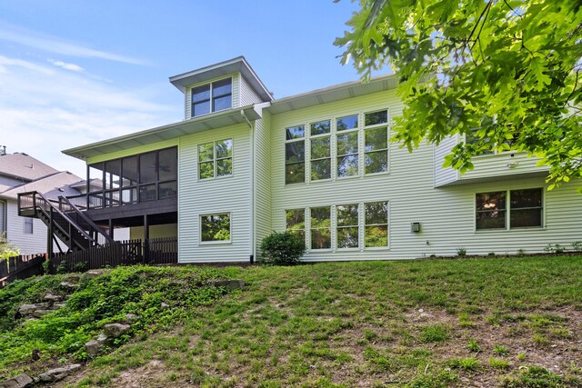 rear view of house featuring a sunroom, a yard, and stairs