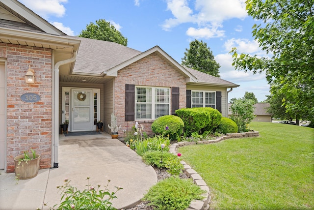 property entrance featuring brick siding, a shingled roof, and a yard