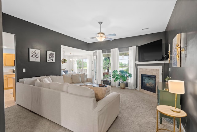 living area featuring ceiling fan, light colored carpet, and a glass covered fireplace
