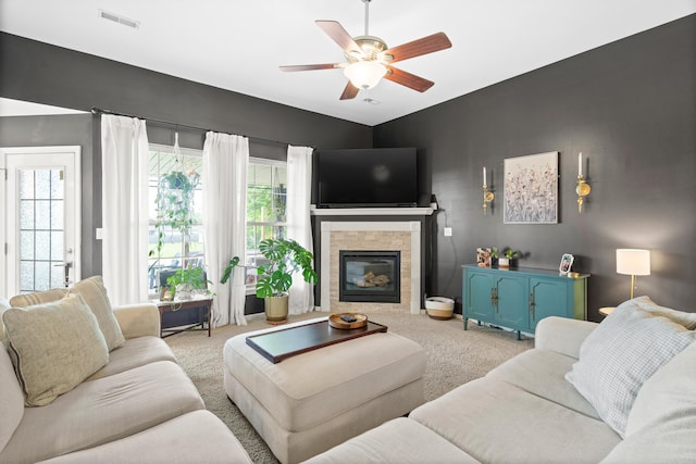 carpeted living area featuring a ceiling fan and a tile fireplace