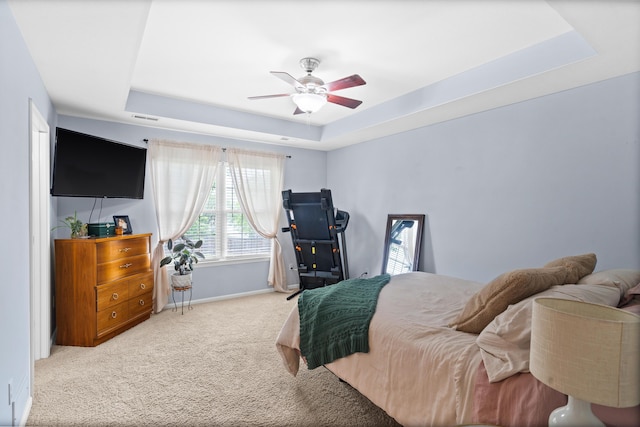 bedroom with a raised ceiling, carpet, baseboards, and ceiling fan