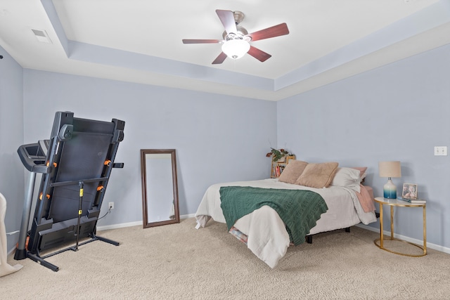 bedroom with carpet, baseboards, a raised ceiling, and a ceiling fan