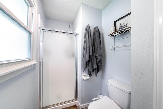 full bathroom with a shower stall, toilet, and a textured ceiling