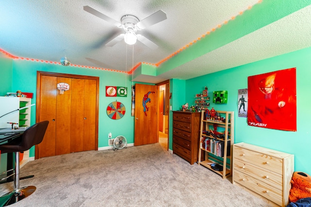 bedroom featuring a textured ceiling, carpet flooring, baseboards, a closet, and ceiling fan
