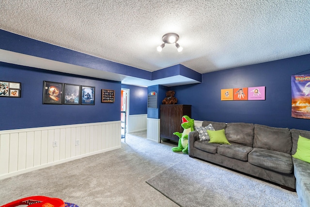 carpeted living area featuring wainscoting and a textured ceiling