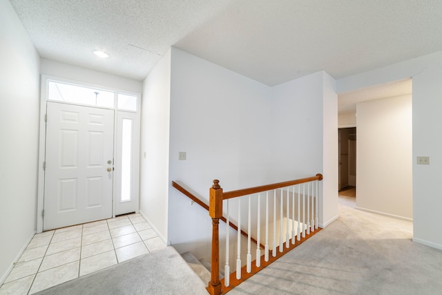 carpeted foyer entrance with baseboards and a textured ceiling