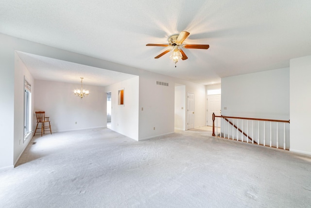 spare room featuring a chandelier, a ceiling fan, light colored carpet, and baseboards