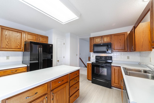 kitchen with black appliances, a sink, backsplash, and light countertops