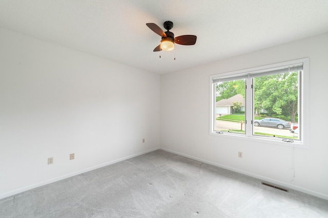 empty room featuring light carpet, a ceiling fan, and baseboards
