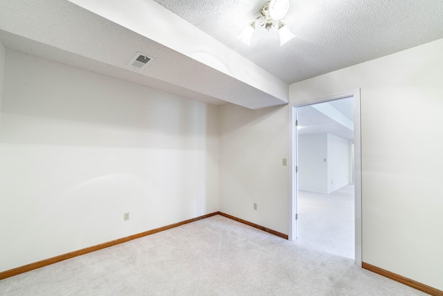 carpeted empty room featuring a textured ceiling and baseboards
