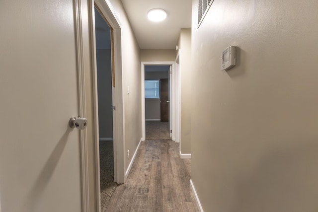 corridor with wood finished floors and baseboards
