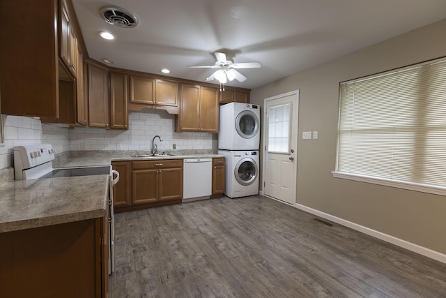 kitchen with white appliances, stacked washer / dryer, a sink, ceiling fan, and backsplash