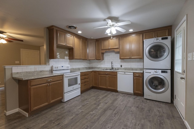 kitchen featuring white appliances, stacked washer and clothes dryer, ceiling fan, a sink, and decorative backsplash