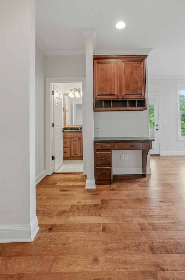 5300 Perche Pointe Pl, Columbia, MO 65203 - kitchen with ornamental molding, light wood finished floors, dark countertops, baseboards, and brown cabinetry